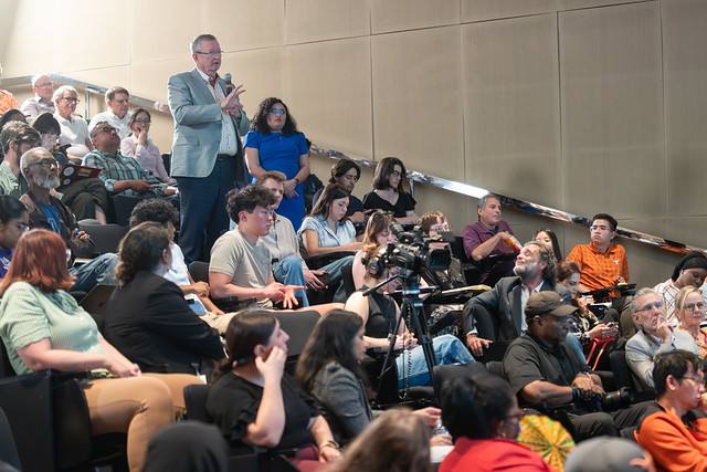 An attendee standing to ask a question during a Forum session
